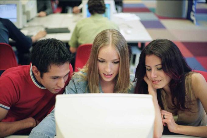 Tres estudiantes atentos a la pantalla de una computadora.