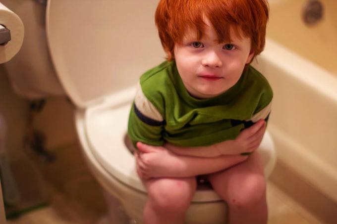 الولد الصغير يجلس على المرحاض