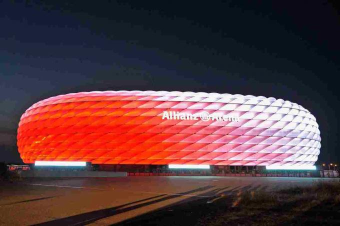 أبيض نهارًا ، يتألق الجزء الخارجي المنحوت من Allianz Arena باللون الأحمر في الليل