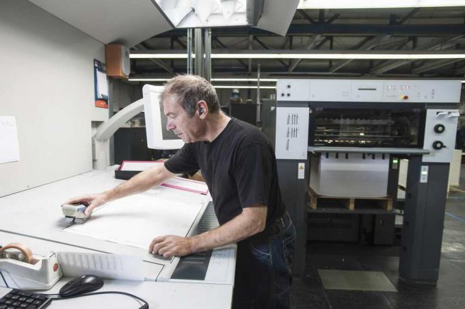 عامل يقوم بتجهيز معدات الطباعة الرقمية في ورشة الطباعة