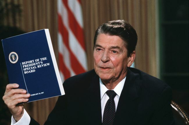الرئيس رونالد ريغان يحمل نسخة من تقرير لجنة البرج حول فضيحة إيران كونترا