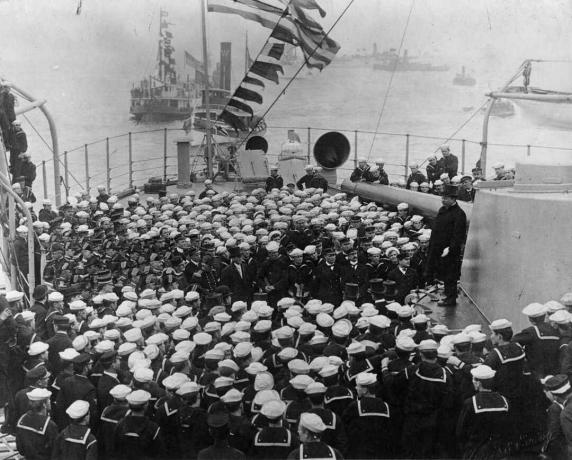 الرئيس ثيودور روزفلت يقف على برج حربية أمامه حشد من البحارة.