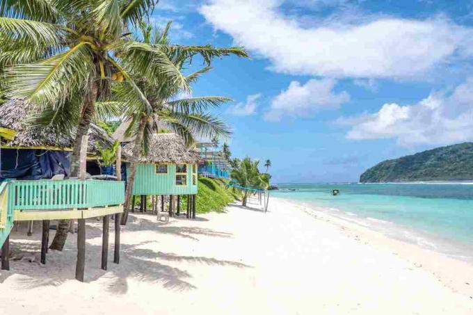 منظر على طول شاطئ Lalomanu ، وجزيرة Upolu ، Samoa ، من أكواخ شاطئ Samoan الوهمية الملونة التي تعد بديلاً عن الإقامة في الفنادق أو المنتجعات