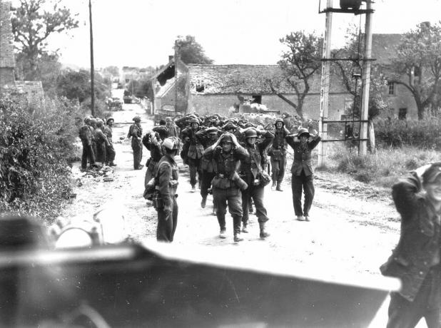 جنود ألمان يسيرون في شارع بأيديهم على رؤوسهم في استسلام.
